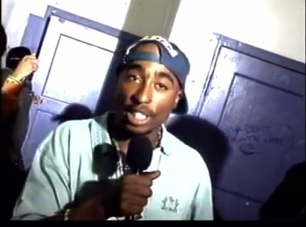 2Pac holding the Shure V64 wireless microphone on Black Watch Television